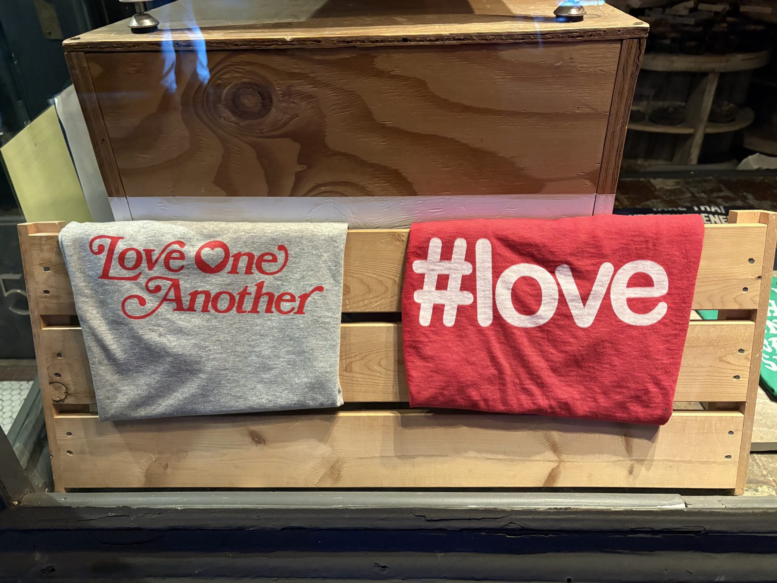 Two t-shirts hanging with a message of love written on them.